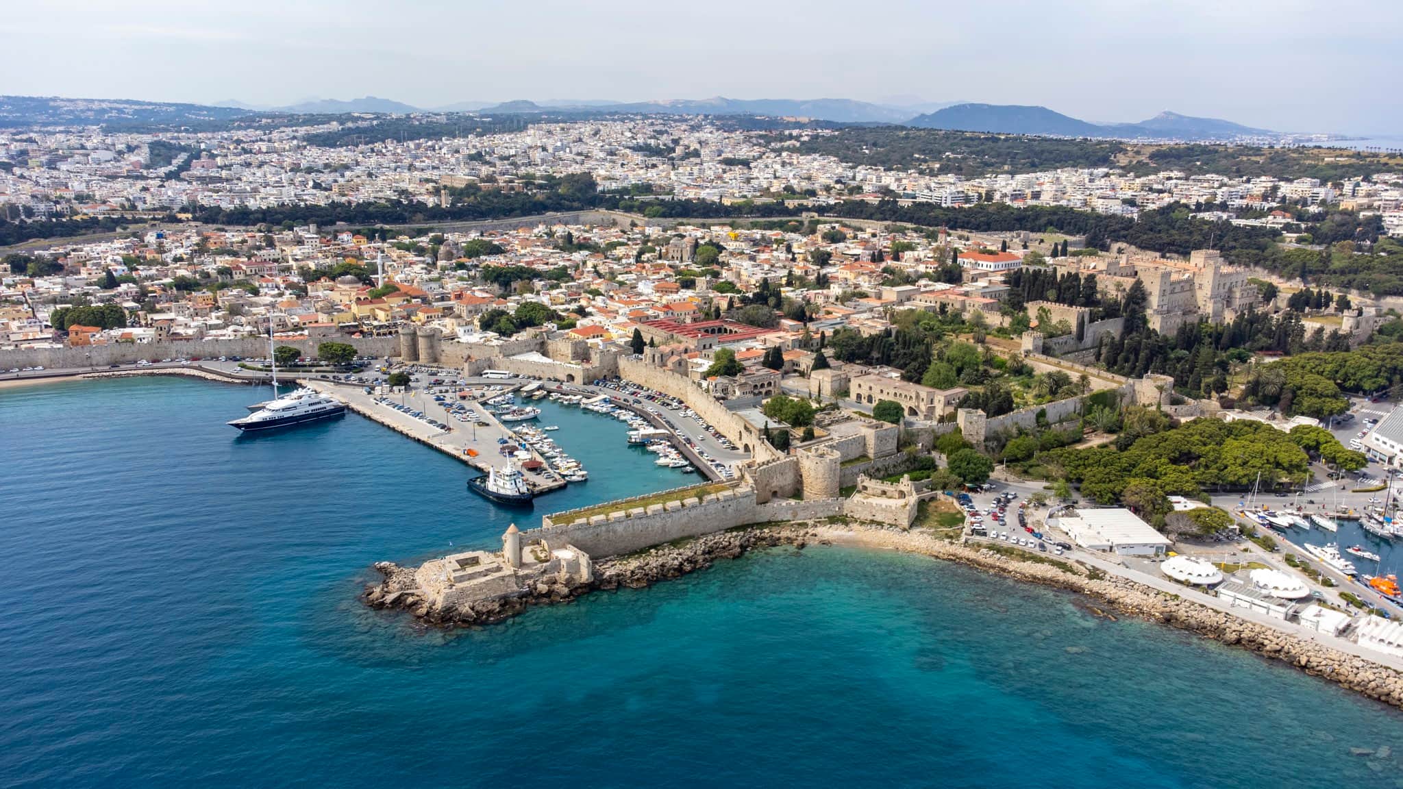 Aerial view of Rhodes Town — the medieval Old Town walls, Mandraki harbour and the Palace of the Grand Master beside turquoise sea